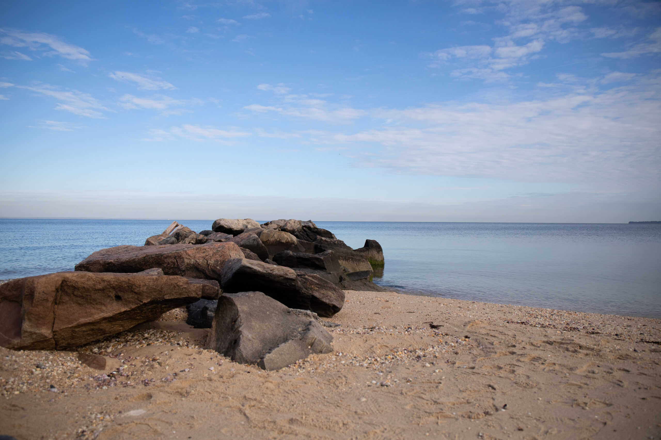 Calm shoreline with a rocky outcrop at Sunken Meadow Park, a potential outdoor wedding photography location.
